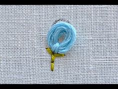 the thread is blue and yellow with a green needle on it's end, next to a piece of fabric