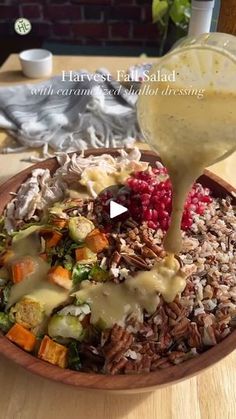 a wooden bowl filled with rice and veggies covered in gravy being drizzled over it