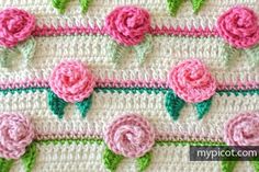 crocheted flowers and leaves on the side of a blanket