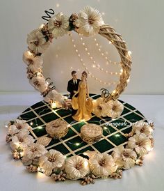 a wedding cake topper with flowers and lights in the shape of a circle on a table