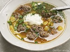 a bowl of soup with meatballs and sour cream