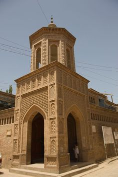 a tall building with a clock on it's side and a person standing in the doorway