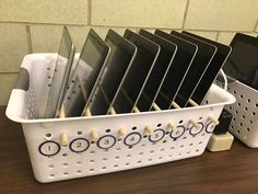 a white plastic basket filled with lots of black and white items on top of a wooden table