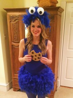 a girl in a blue dress is holding a cookie