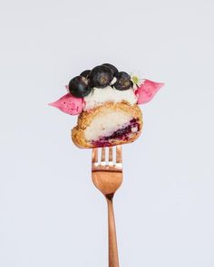 a piece of cake sitting on top of a wooden fork with berries and whipped cream