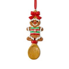 a christmas ornament hanging from a red ribbon on a white wall with a gold spoon