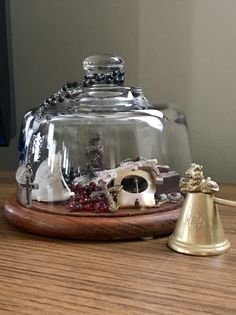 a glass clochet on a wooden table next to a bell and other items