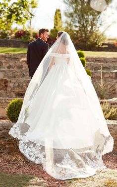 a bride and groom standing in front of some stone steps with their veil blowing in the wind