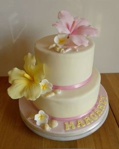 a three tiered cake with flowers on the top and happy birthday written on the side