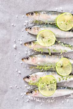 five fish with lemon slices and herbs on top of them next to salt and pepper