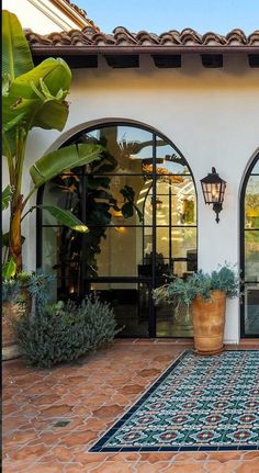 an outdoor patio with potted plants and two large doors leading into the back yard