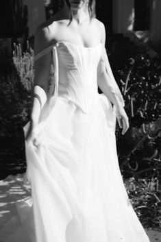 a woman in a white dress walking down the street with her hand on her hip