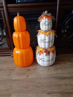 three pumpkins stacked on top of each other in front of a fireplace