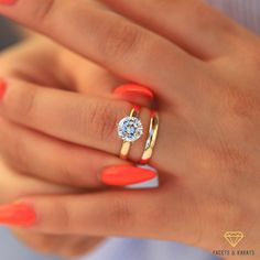 a woman's hand with two rings and an orange manicured nail polish on it