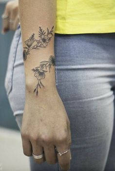 a woman's hand with a flower tattoo on her left wrist and the other arm