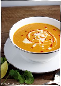 a white bowl filled with soup on top of a plate next to cilantro