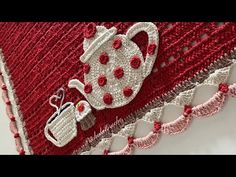 a crocheted red and white pillow with a tea pot on it