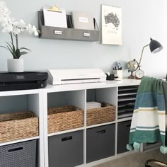 a desk with some baskets on it and a printer in the corner next to it