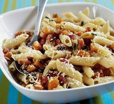 a white bowl filled with pasta and sauce on top of a blue striped table cloth