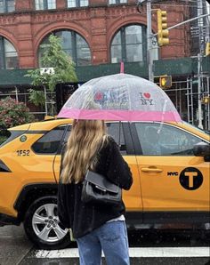 a woman standing in front of a yellow taxi cab with an umbrella over her head