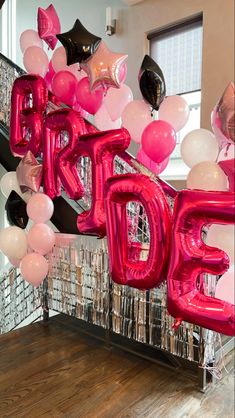 balloons and streamers spell out the word hope in front of a staircase decorated with black, pink, and white balloons