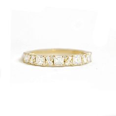 a yellow gold wedding band with three princess cut diamonds on the side and two rows of baguettes in the middle