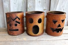 three brown pots with faces painted on them