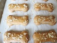 dog treats are lined up on a sheet of parchment paper with sesame seeds in them