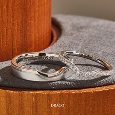 two wedding rings sitting on top of a wooden table