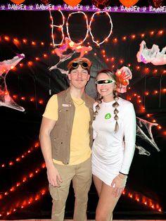 a man and woman standing next to each other in front of a wall with lights