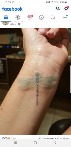 a woman's arm with a small dragonfly tattoo on the left side of her wrist