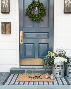 a blue front door with two buckets and flowers