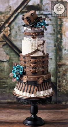 a multi layer cake with blue flowers and ribbons on the top is sitting on a stand