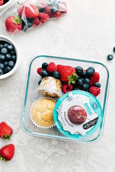 berries, blueberries, and muffins in a plastic container on a table