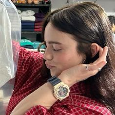 a woman wearing a red and white checkered shirt looking at her watch