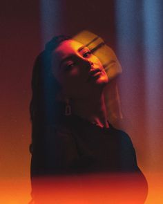 a woman with long hair standing in front of colorful lights and looking up at the sky