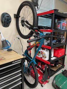 a bike is hanging on the back of a garage shelving unit with tools in it