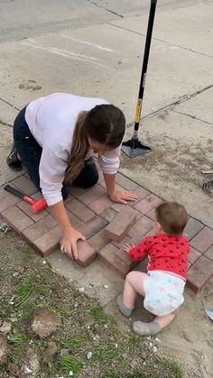 a woman kneeling down next to a little boy on the ground near a fire hydrant