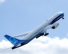 a large jetliner flying through a blue sky with white clouds in the foreground