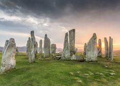 the stonehenge monument stands in an open field at sunset, with dark clouds overhead