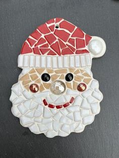 a mosaic santa clause ornament on a black surface