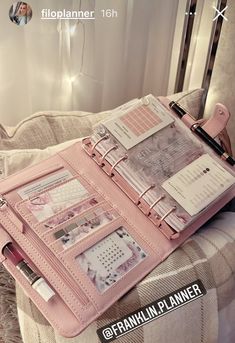 an open pink planner sitting on top of a bed