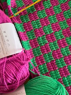 the yarn is pink and green, with a ball of knitting needles next to it