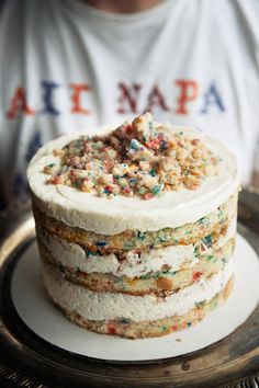 a cake with white frosting and sprinkles on it sitting on a plate