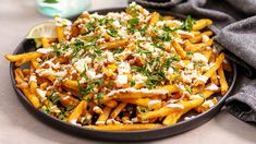 a plate full of french fries topped with cheese and herbs