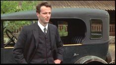 a man in a suit standing next to an old truck