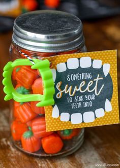 a jar filled with candy sitting on top of a wooden table next to a sign that says something sweet to sink your teeth into