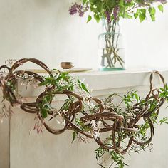 a bunch of vines hanging from the side of a window sill next to a vase with flowers in it