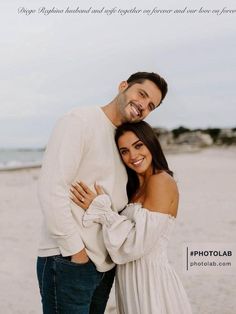 a man and woman standing next to each other in front of the ocean on a beach