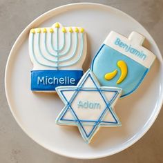 three decorated cookies on a plate with the names of different jewish symbols and menorah